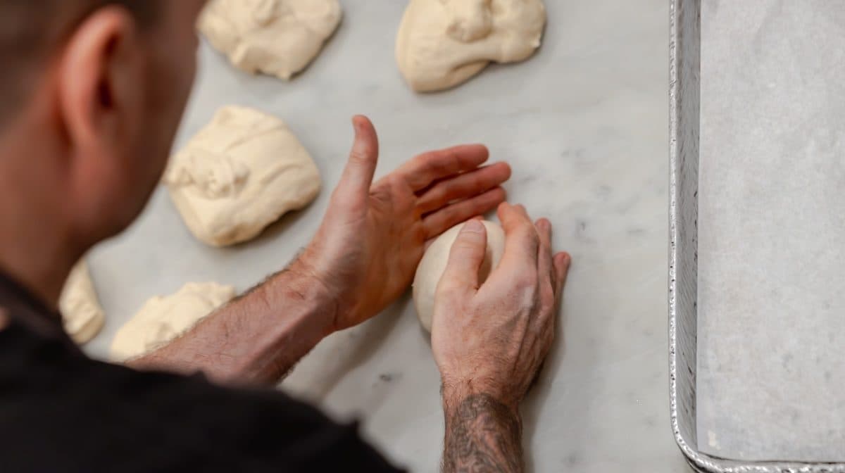 a man rolls dough on a countertop